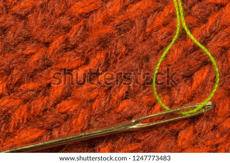 Needle with thread on red textile background. macro view