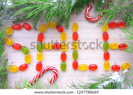 Christmas sign sale made from caramel candies with snowy fir tree branches on wooden table background