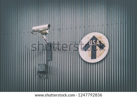 Surveillance camera with vintage USA direction sign on a steel wall