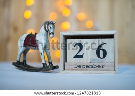 Cube wooden calendar showing date on 26th December with old toy rocking horse over bokeh background. Advent calendar, Christmas background, Copy space