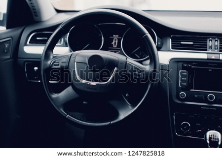 Steering wheel in a new car. Steering wheel with control buttons. Modern car interior in black color.