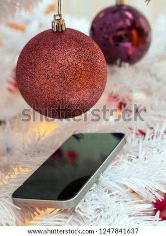 Picture shows a Christmas bauble with a cell phone on a white tree
