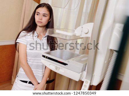 A pretty young girl near a mammographer - an X-ray machine with the help of which breast examinations are performed to prevent or detect tumors and breast cancer.