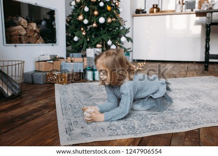 Girl playing with Christmas decoration. Christmas gift boxes on background