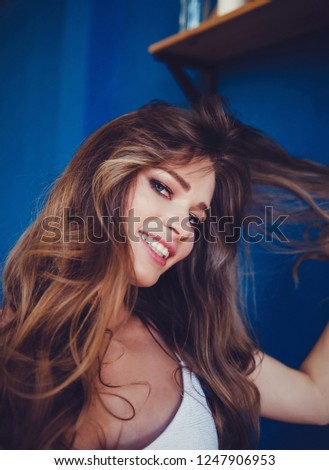 Portrait of a smiling cute woman making selfie photo on smartphone on blue background
