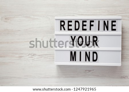 'Redefine your mind' words on lightbox over white wooden surface, top view. Overhead, flat lay, from above. Copy space.