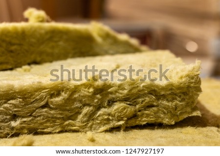 Thermal insulation material, rock wool. Thermal roof insulation layer. Mineral wool or mineral fiber, mineral cotton, mineral fibre, glass wool, MMMF, MMVF. Fiber thermal insulation close-up. Royalty-Free Stock Photo #1247927197