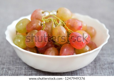 Grapes in a porcelain plate. Ripe pink Muscat grapes.