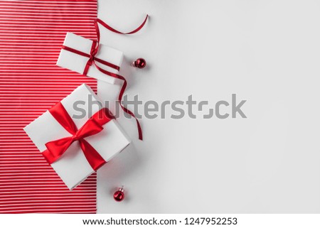 Christmas gift boxes with red ribbon, decoration on white and red paper background. Xmas and Happy New Year theme. Flat lay, top view, space for text