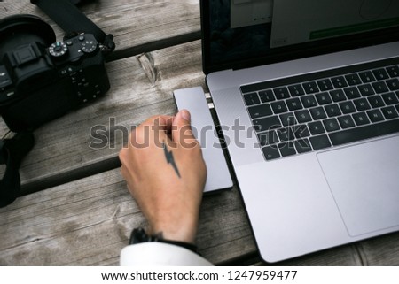 Flat lay table top view of photographer hand with tattoo insert multifunctional multi port cardreader into new usb-c adaptor laptop. File and data transfer concept, fast information exchange