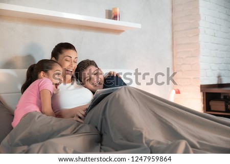 Single mother, family and people. Woman streaming movie on laptop computer in bed, watching show with her son and daughter
