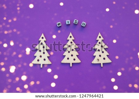 New Year wooden ornaments, top view. Wooden Christmas tree. Violet background. Flat lay style. Place for text. Christmas concept. Inscription wish. Festive picture with lightening golden bokeh lights