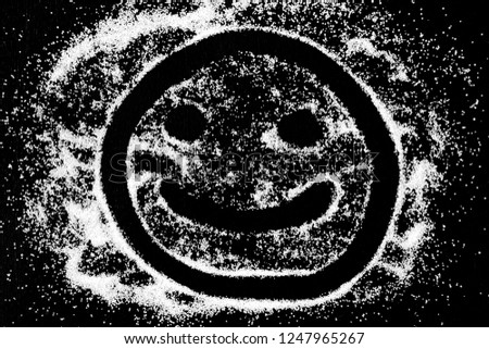 Symbol happy smile emoticon drawing by finger on white snow salt powder on black background. Concept with place for text. Copy space.