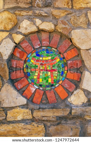Circular mosaic religious symbol of Shinto on stone wall.