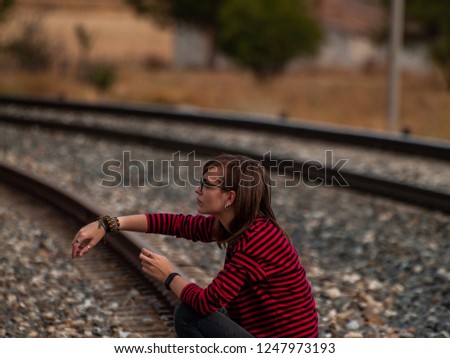 A lonely teen girl sitting on the train tracks