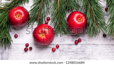 Christmas background with tree branches, red apples and cranberries. Light wooden table. Top view. Copy space