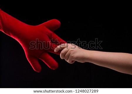 Cute little boy hand holding big red soft toy hand. Young boy and his imaginary friend. Pediatrics comforting toy