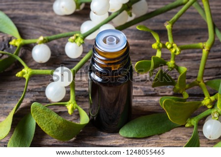 A bottle of essential oil with fresh mistletoe