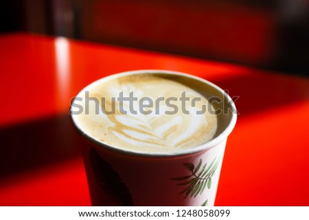 the picture on the foam of the cappuccino in the Cup on red background