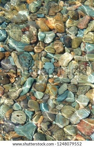 colorful pebble stone view with wave and clear sea, underwater, background, texture