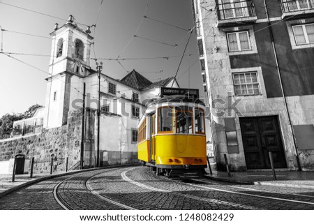 Black and white picture of a yellow tram on the streets of Lisbon, Alfama, Portugal near Santa Luzia church
