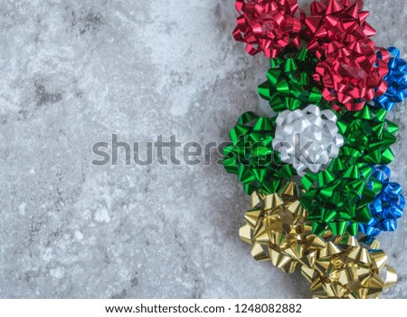 vertical border of bright Christmas and Hanukkah gift bows on a gray marble counter top