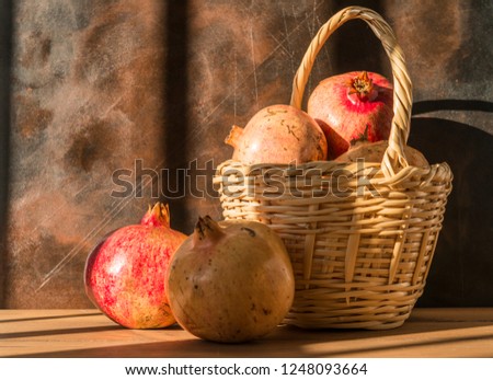 Healthy food concept. Still life with wicker basket with pomegranates on wooden table.