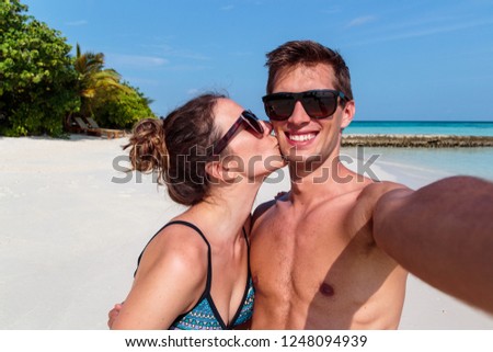 man and woman in 
swimsuit taking a self portrait picture during holiday. turquoise water as background