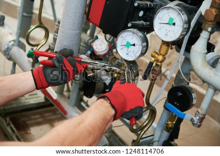 heating engineer or plumber in boiler room installing pipeline manometer Royalty-Free Stock Photo #1248114706