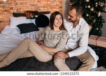 Couple at home near Christmas tree on the background. Couple in love on bed