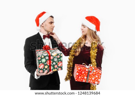 A happy couple of lovers, in Santa Claus hats, celebrates the New Year, with Christmas gifts in their hands. On a white background.