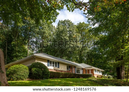 American home, ranch home around green trees, one level home.  Royalty-Free Stock Photo #1248169576