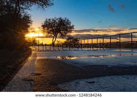 A colorful sunrise on The Loop, a biking, walking, jogging and running path or trail that circles the city of Tucson, Arizona. Rain puddles offer mirror like reflections of the beautiful sky. 2018.