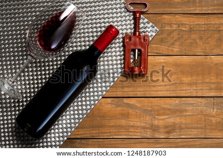 Bottle of wine glass and corkscrew on wooden background. Top view with copy space.