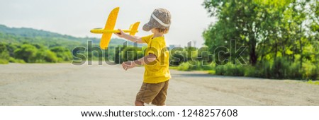 Happy kid playing with toy airplane against old runway background. 