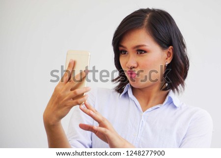 young beautiful asian lady looking at smartphone mobile phone with exciting face. Image suitable for online internet sales.