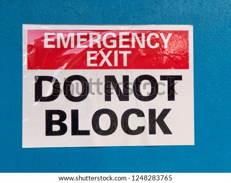 Emergency Exit Do Not Block sign on blue background