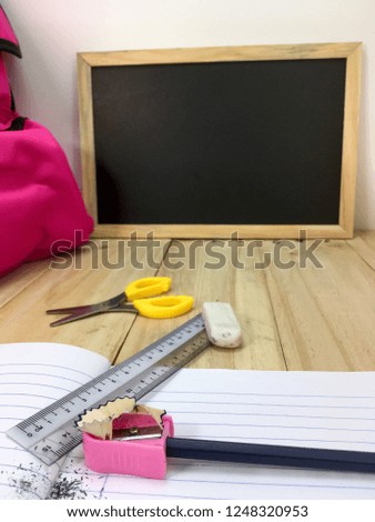 Ruler, eraser. pencils, book, bag, scissors and black board on a wooden table background. Education, Examination or Back to School concept.