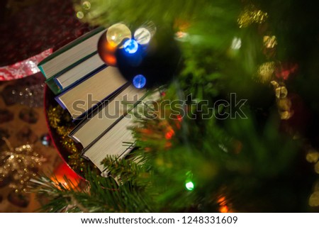 Five books in a gift box under a Christmas tree decorated with balls and garlands