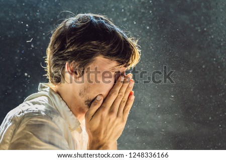 Allergy to dust. A man sneezes because he is allergic to dust. Dust flies in the air backlit by light Royalty-Free Stock Photo #1248336166