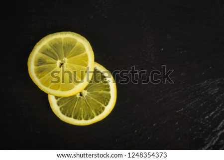 two fresh lemon slices on black background with copy space on right