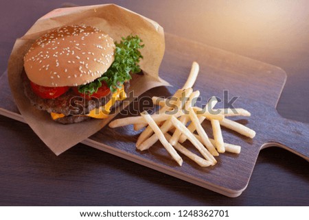 Closeup of homemade hamburger with fresh vegetables on wooden tray, hamburger with french fries