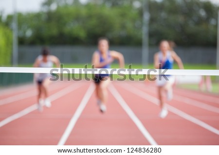 Female athletes running towards finish line on track field Royalty-Free Stock Photo #124836280