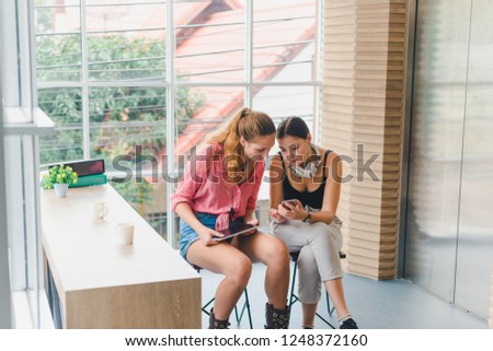 Two beautiful young women playing phone and tablet. concept of relaxation.