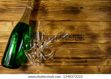 Champagne bottle and two empty champagne glasses on wooden background. Top view, copy space