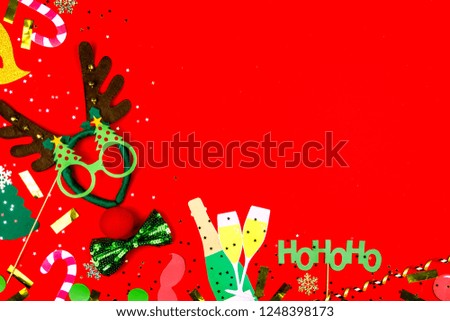 Christmas party props: Christmas Santa's deer, champagne, sweet canes, Santa's HoHoHo, glass of champagne and pine tree glasses, tie bow isolated on red background. Merry Christmas and Happy New Year.