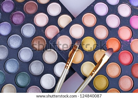 close up picture of multicolor palettes with eyehadows and two brushes