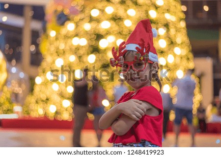 Portrait of cheerful happy girl wearing Christmas deer glass costume, Christmas Hat and action posing with Christmas tree light background.