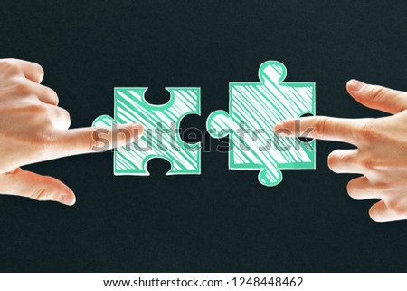 Hands with drawn puzzle pieces on black background. Teamwork and team concept 