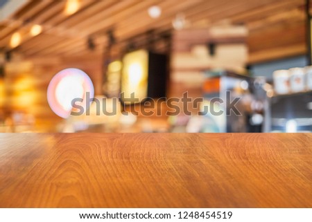 a wooden table with background of blurry modern cafe restaurant interior in a bright day light